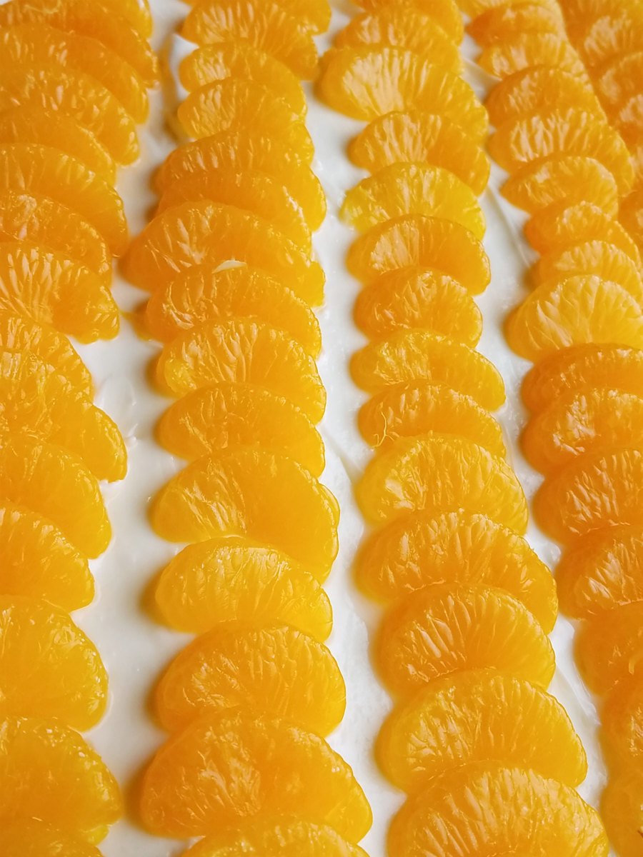 Mandarin orange slices arranged over cream cheese layer.