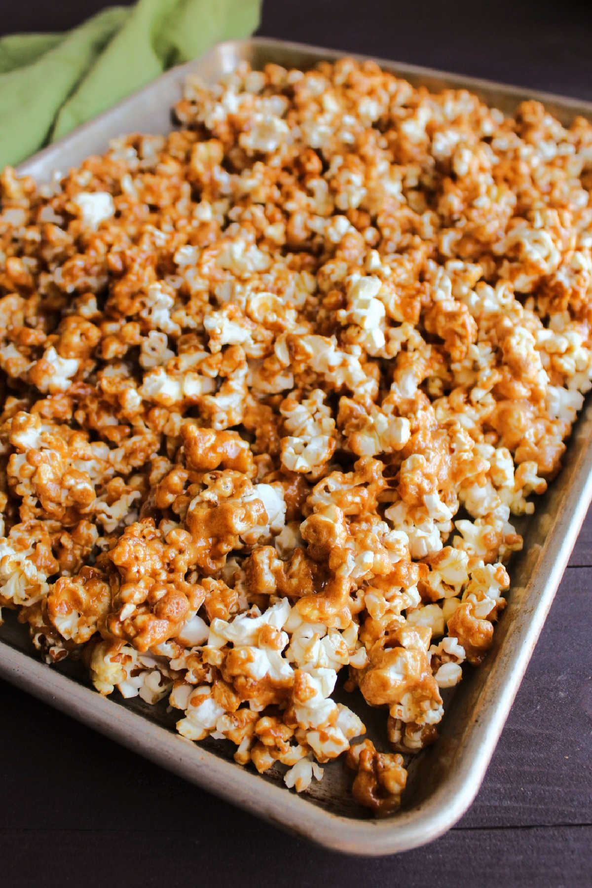 Rimmed half sheet pan filled with peanut butter coated popcorn fresh from the oven.