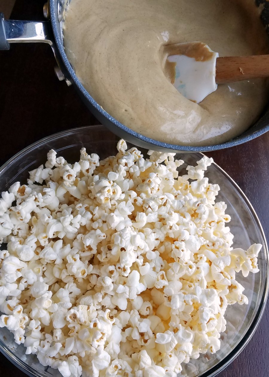 pouring peanut butter caramel mixture over bowl of popcorn