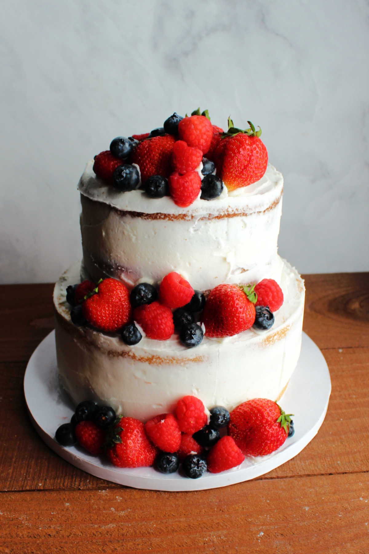 Tiered semi-naked wedding cake decorated with strawberries, raspberries and blueberries.