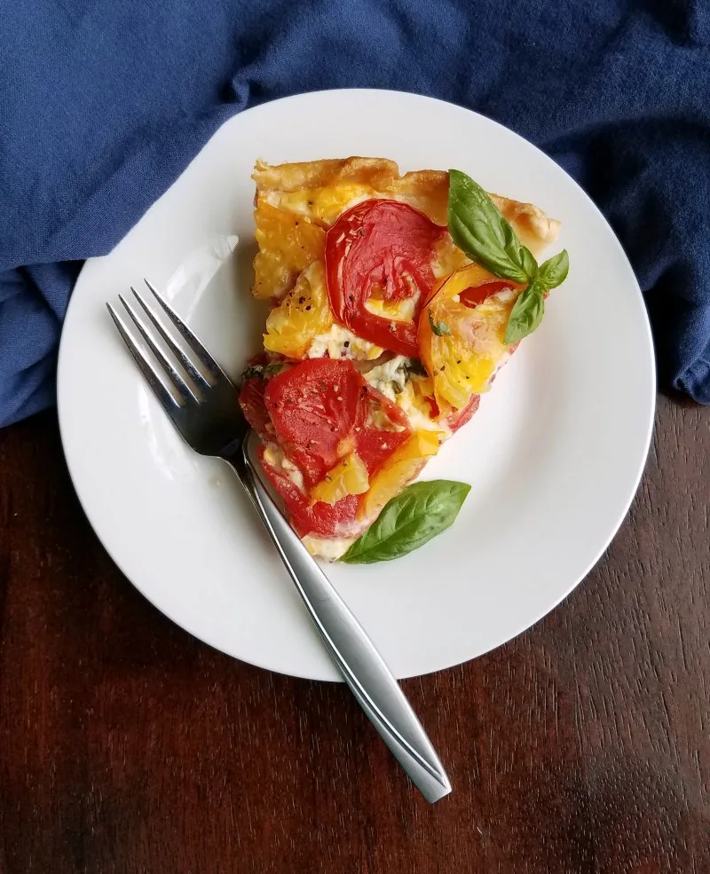 slice of cheesy tomato pie with basil and fork