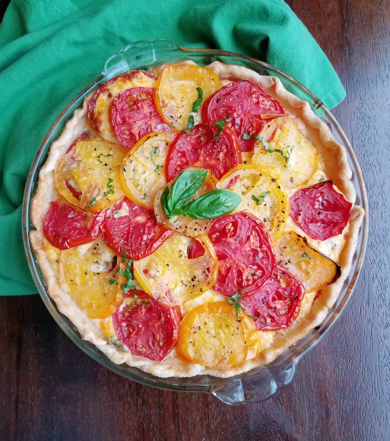 whole tomato pie with yellow and red tomatoes and basil