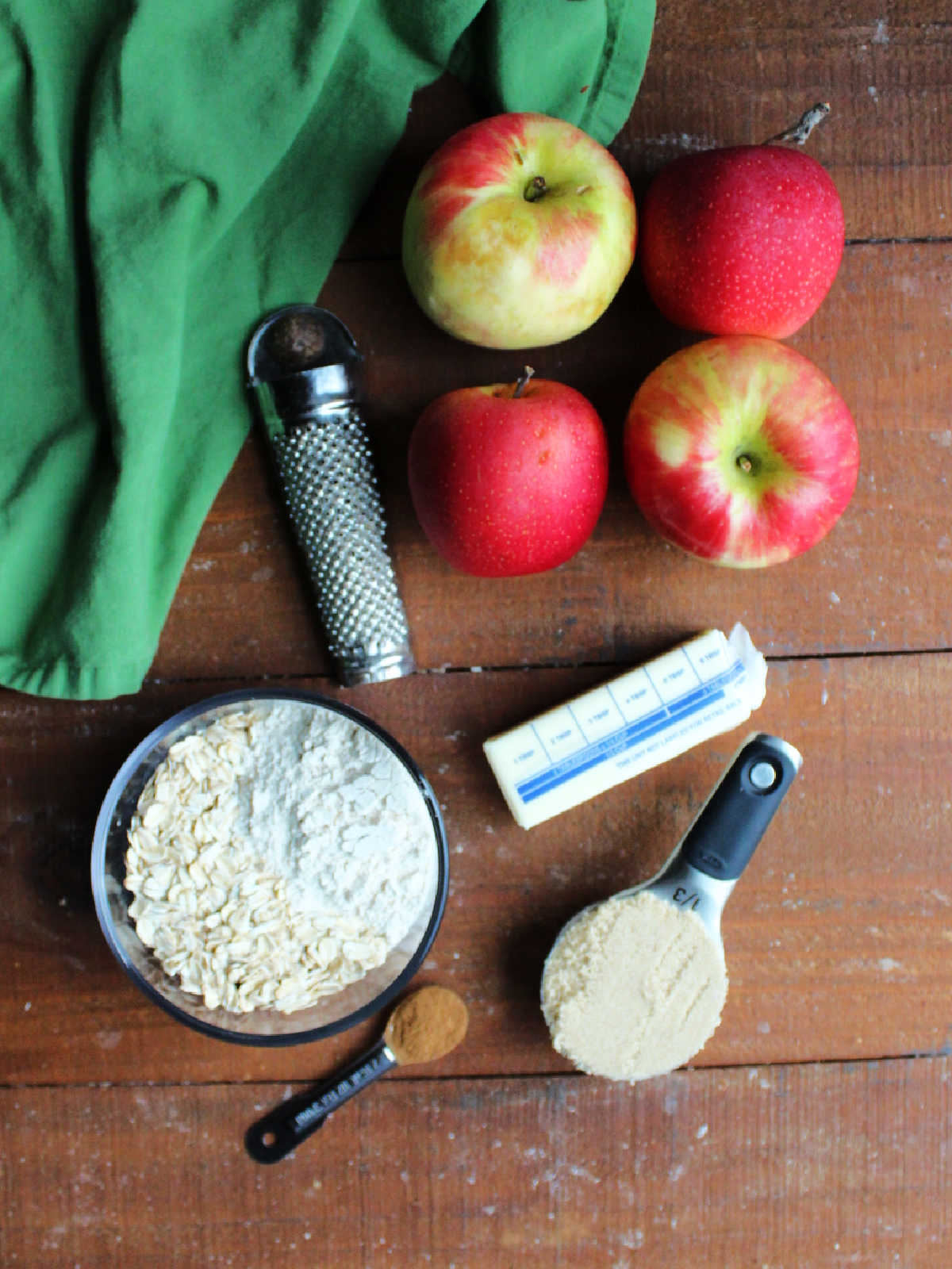 Ingredients including apples, butter, brown sugar, flour, oats, cinnamon, and nutmeg ready to be made into stuffed baked apple halves.
