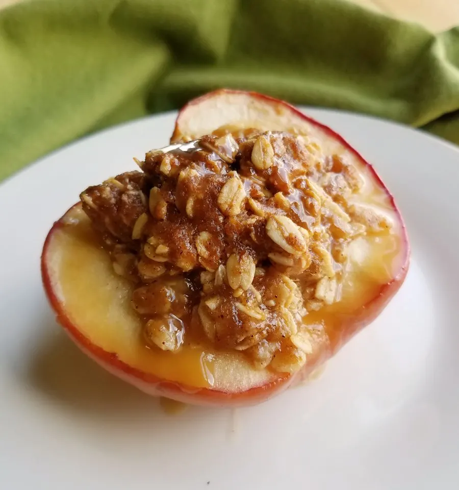 close up of an apple half transformed into a mini apple crisp baked apple with a drizzle of caramel sauce.
