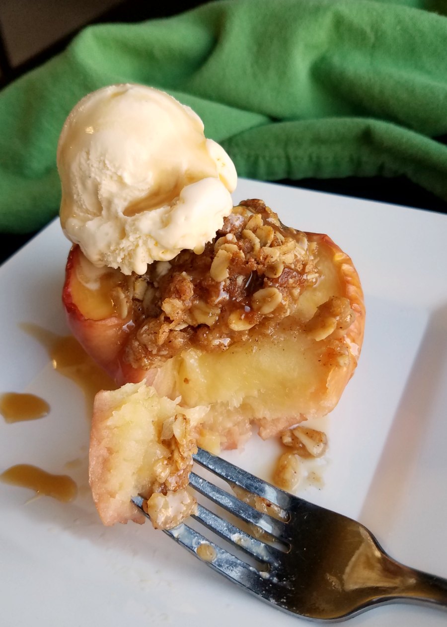 apple crisp baked apple with bite on fork and scoop of vanilla ice cream