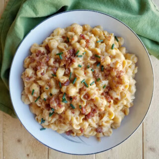 serving bowl filled with mac and cheese topped with bacon crumbles and chives.