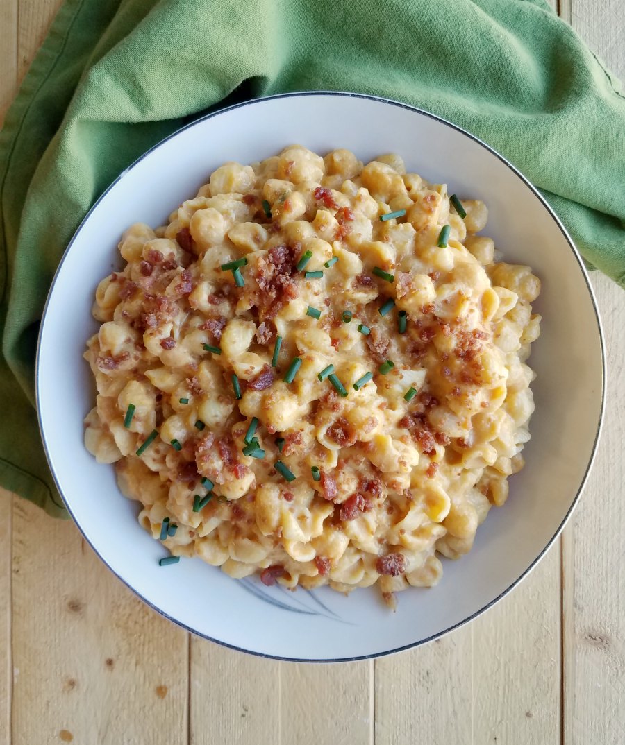 serving bowl filled with mac and cheese topped with bacon crumbles and chives