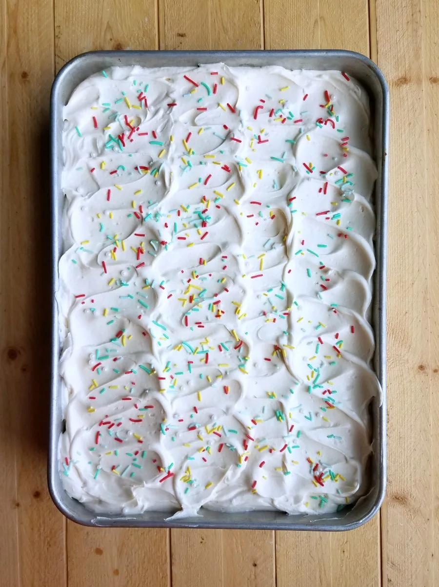 9x13" pan filled with cake topped with swirls of sweetened condensed milk frosting.
