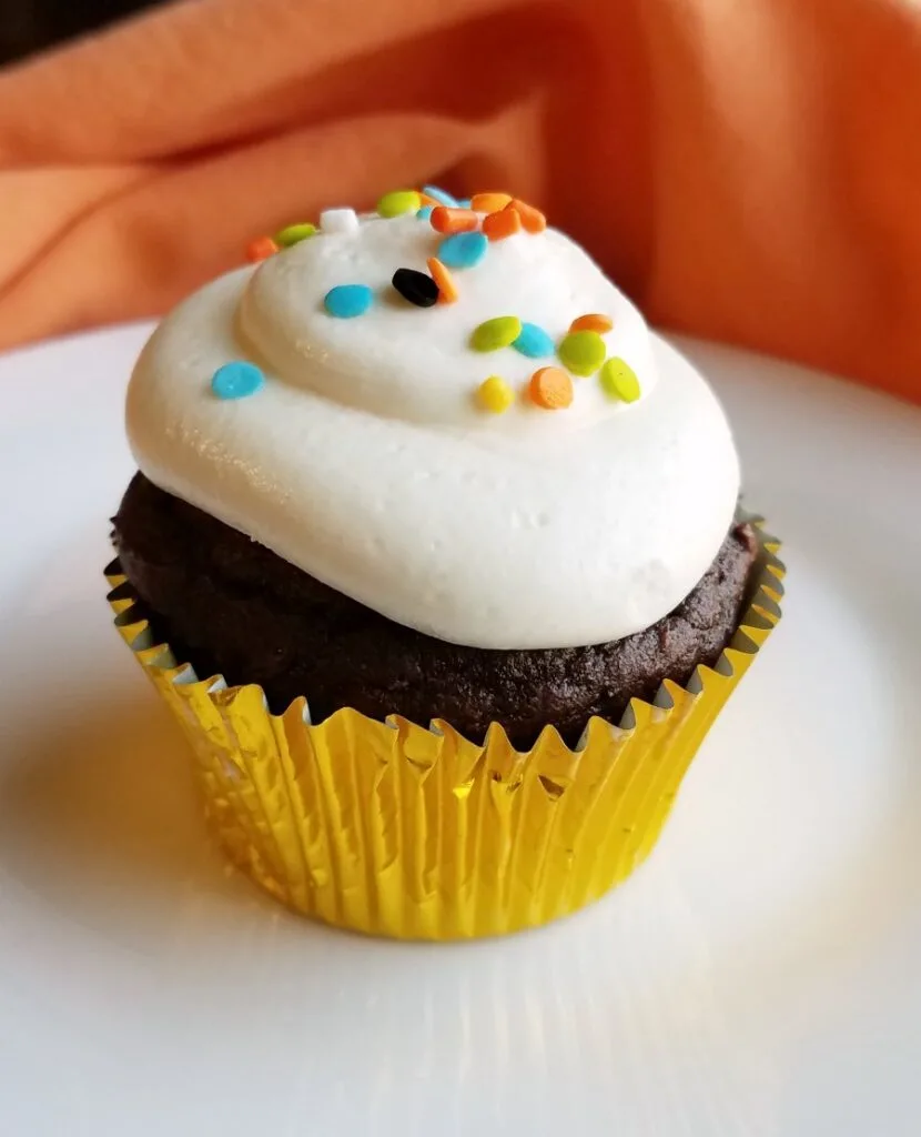 chocolate pumpkin cupcake topped with smooth white whipped sweetened condensed milk frosting.