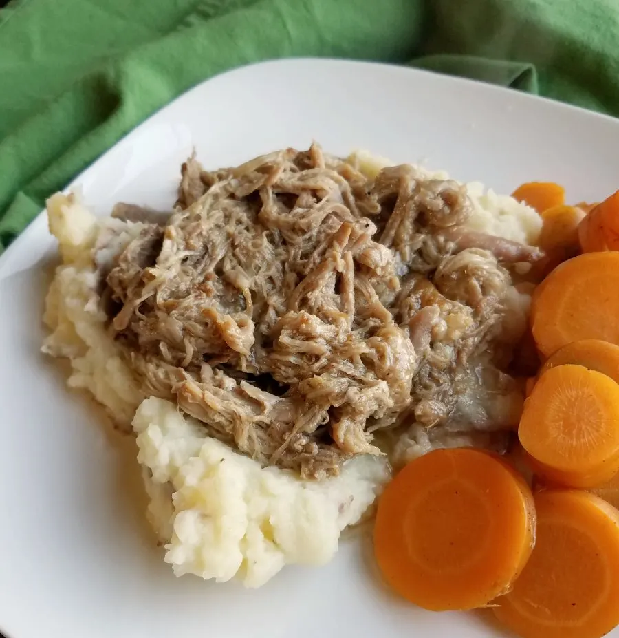 apple cider pulled pork on mashed potatoes with carrots close up.