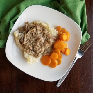 dinner plate with apple cider pulled pork, mashed potatoes and sliced carrots.