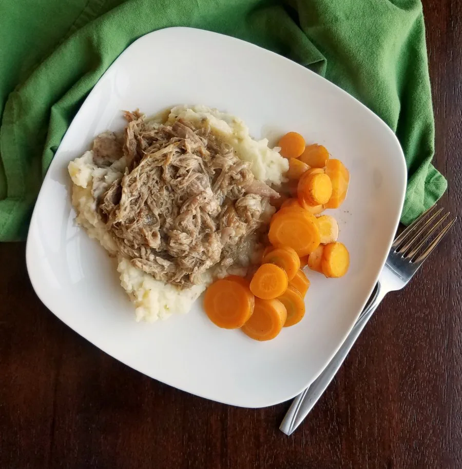 dinner plate with apple cider pulled pork, mashed potatoes and sliced carrots.