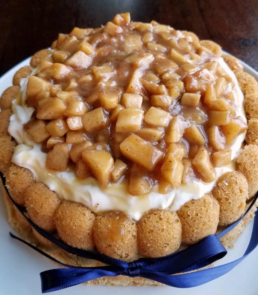 close up of cinnamon sponge filled with cream cheese filling and topped with caramel apples.