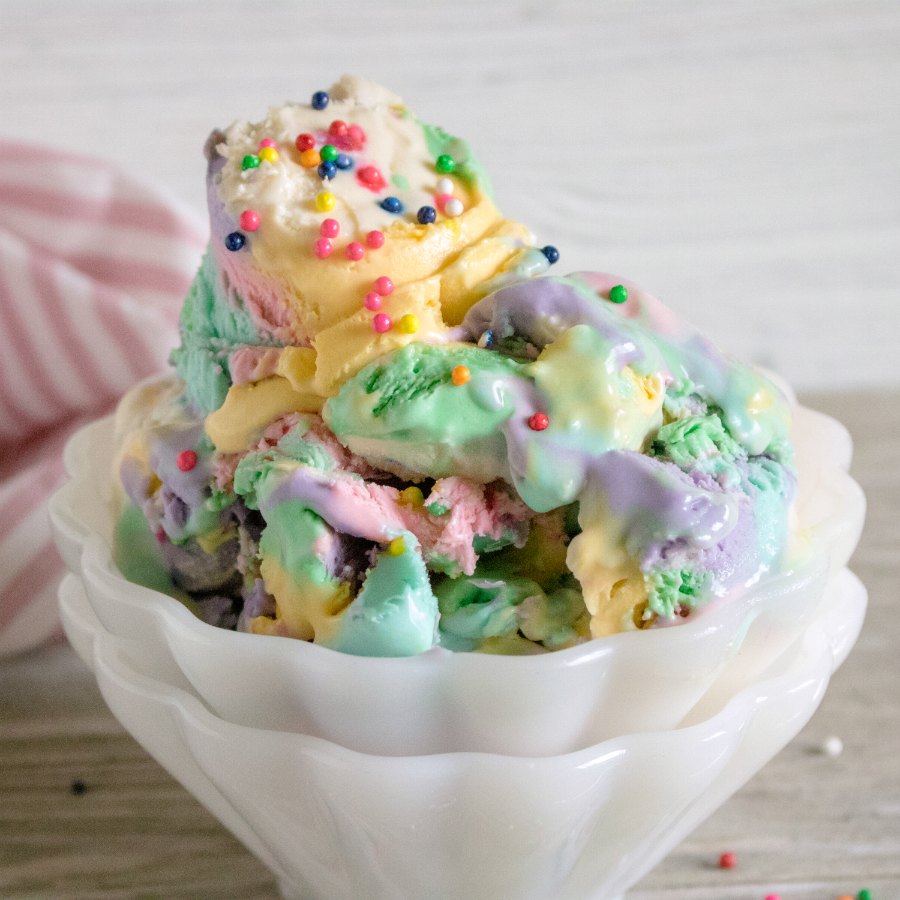 frilly white bowl filled with colorful ice cream with sprinkles on top.