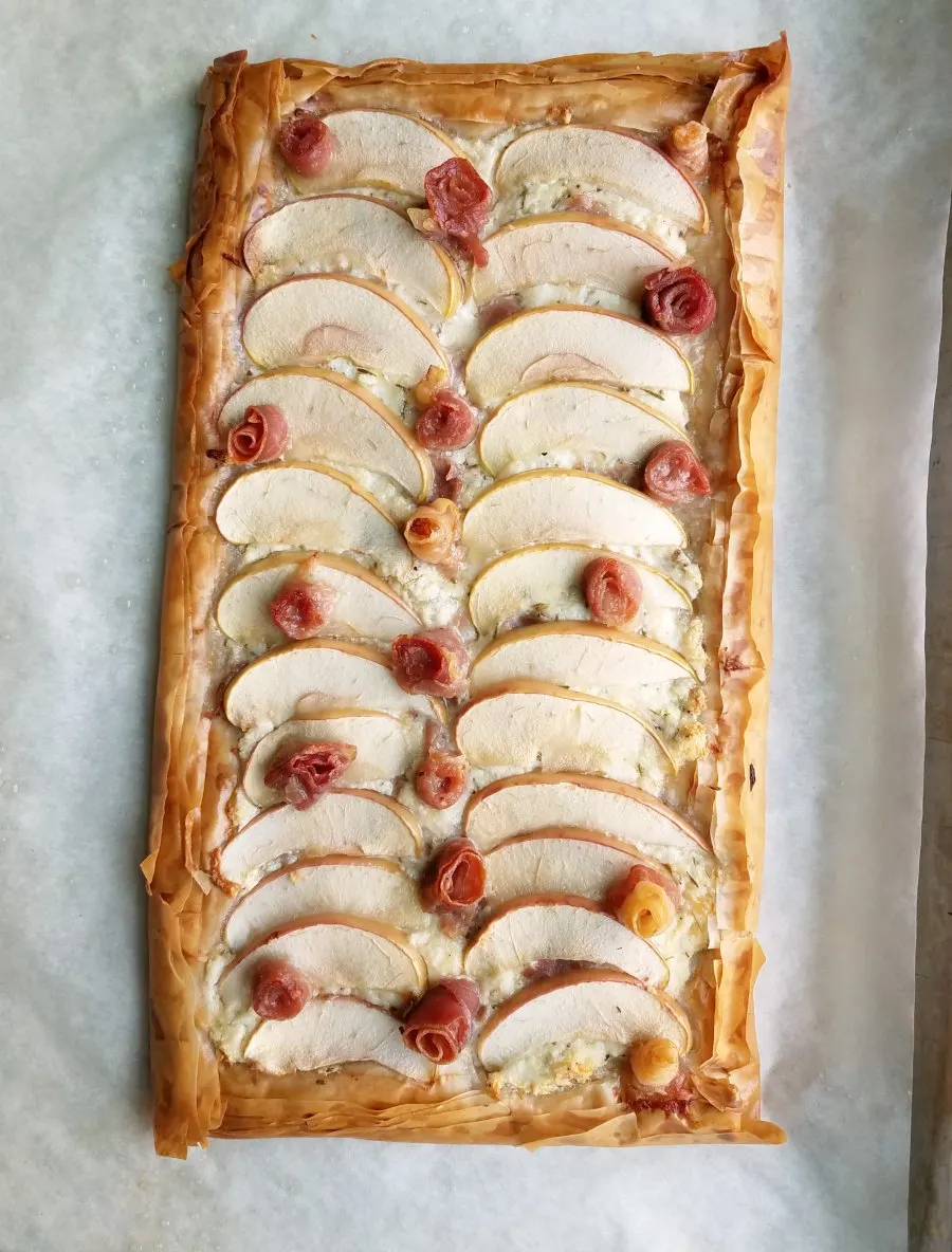 whole ricotta tart with golden flaky phyllo crust, apples, ricotta and prosciutto roses