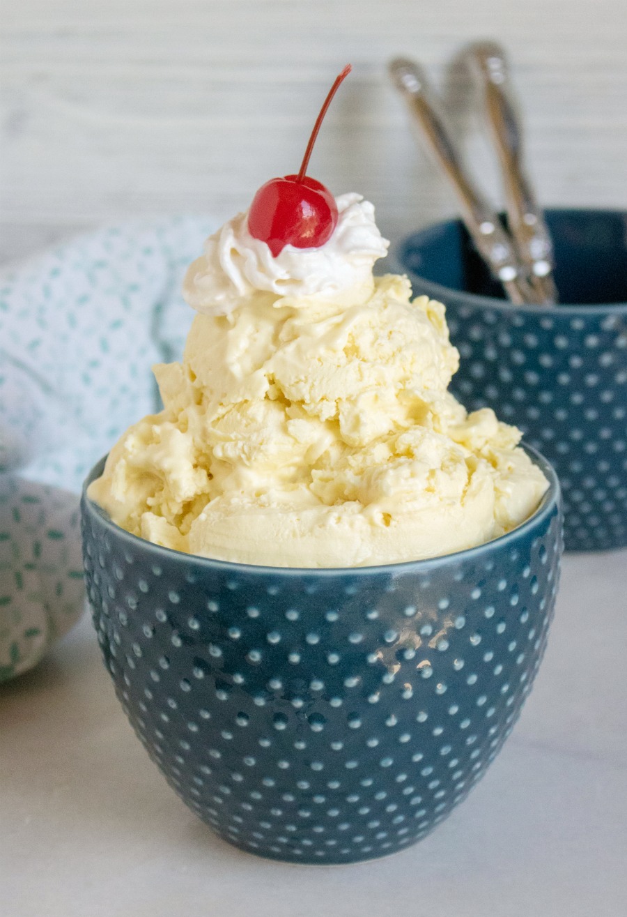 Bowl of lemonade ice cream topped with whipped cream and cherry.