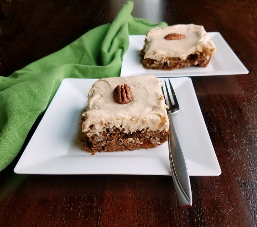 two pieces of cake with cream cheese icing and pecans