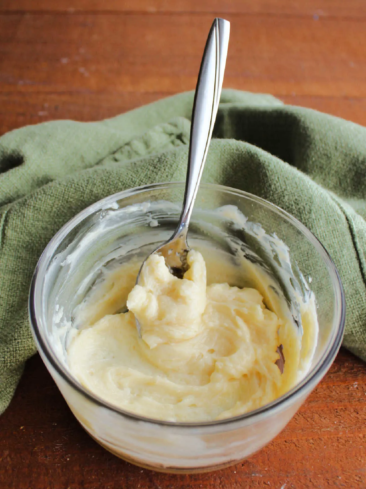 Small glass bowl of vanilla honey butter with spoon, ready to be spread on bread.
