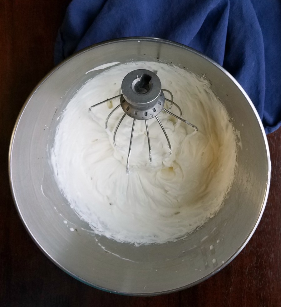 Mixer bowl filled with cream cheese whipped cream for topping cheesecake.