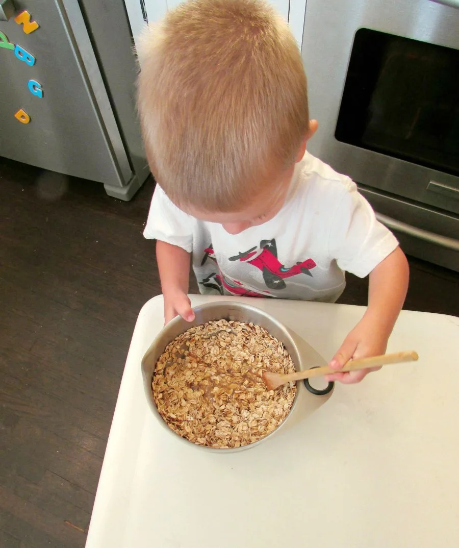 little dude stirring bowl of cinnamon oatmeal to bake.
