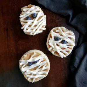 english muffins decorated with peanut butter and cream cheese mummy bandages with blueberry eyes