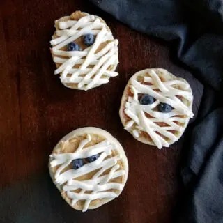 english muffins decorated with peanut butter and cream cheese mummy bandages with blueberry eyes