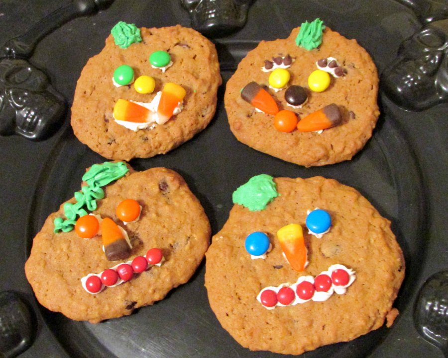 variety of candy faces on pumpkin cookies.