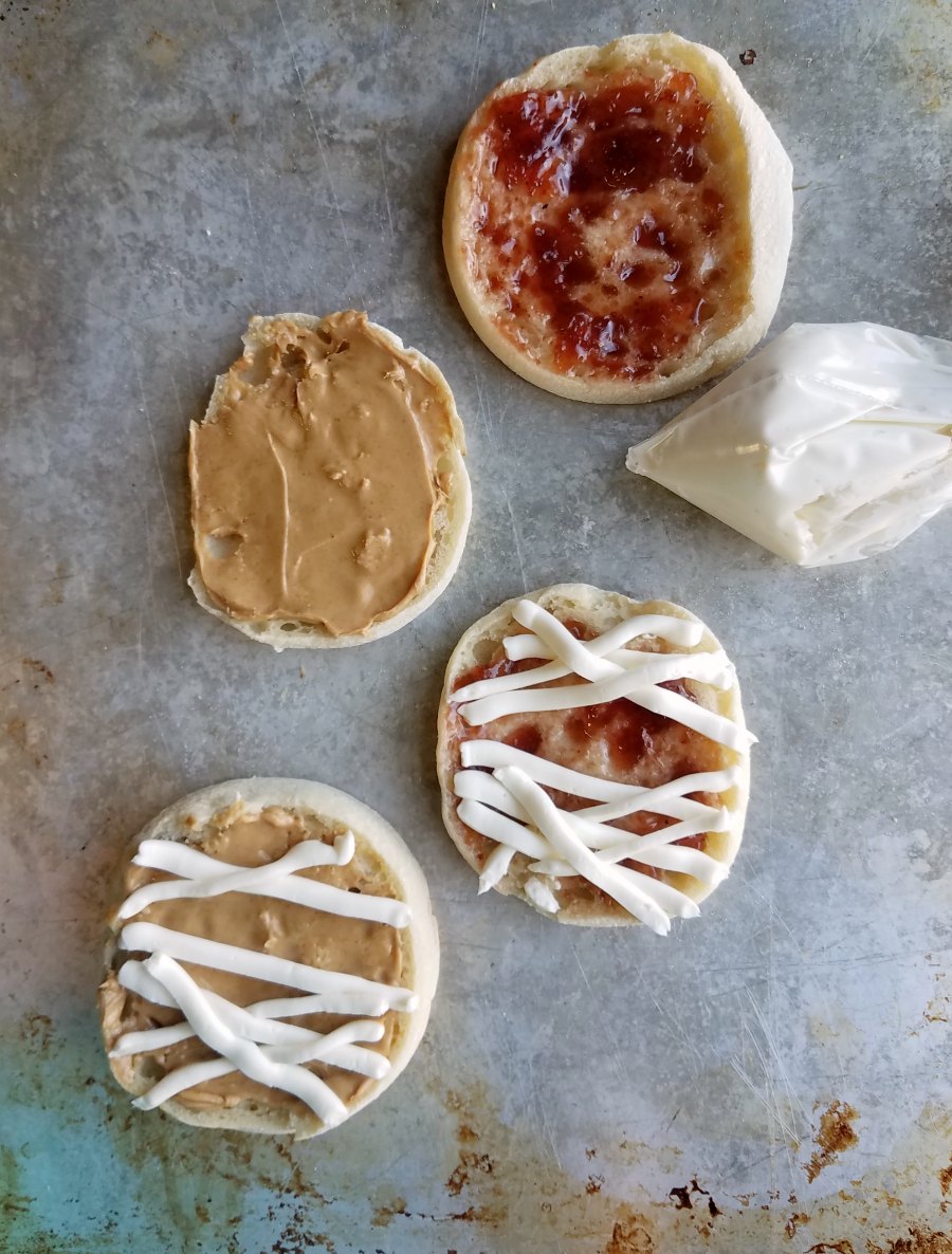 baggie of cream cheese mixture piping out bandages over english muffins.