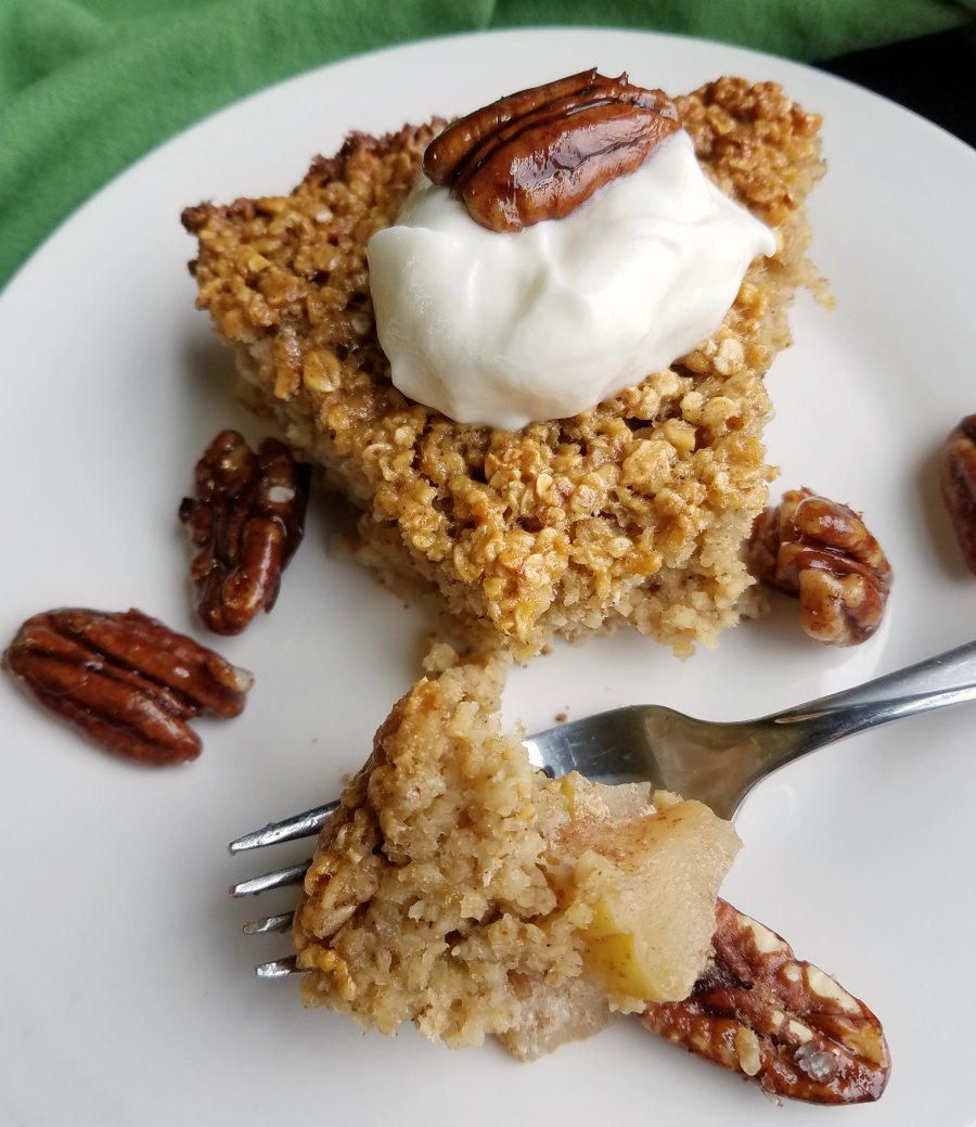 Apple pie baked oatmeal served with vanilla yogurt and honeyed pecans, ready to eat.
