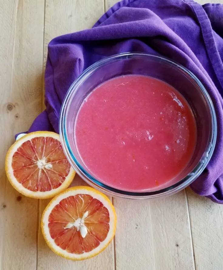 bowl of pink orange curd with blood orange halves nearby.