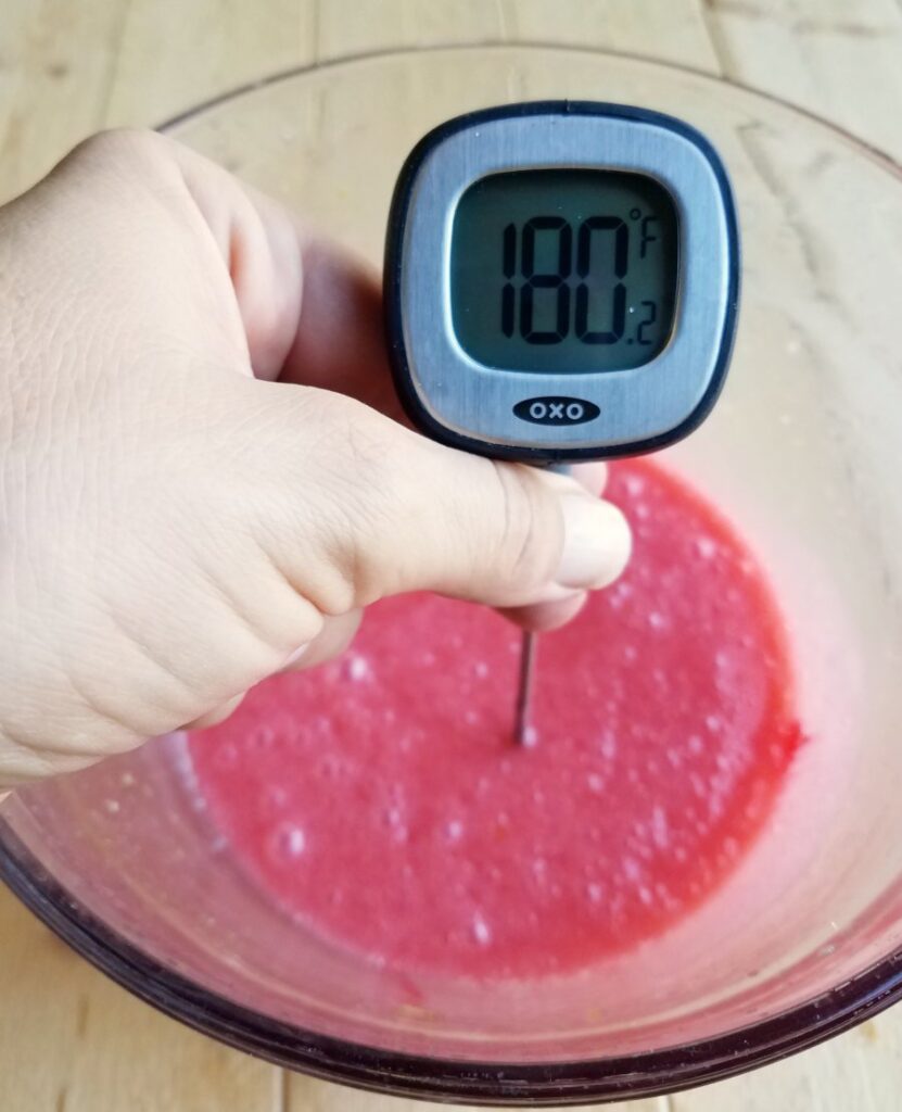 digital thermometer reading 180 F in bowl of pink orange curd.