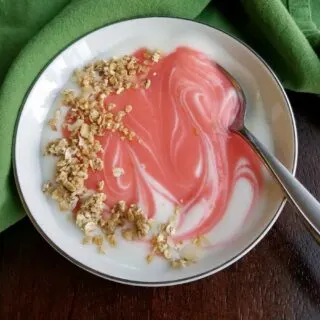 swirl of pink blood orange curd in yogurt with sprinkling of granola