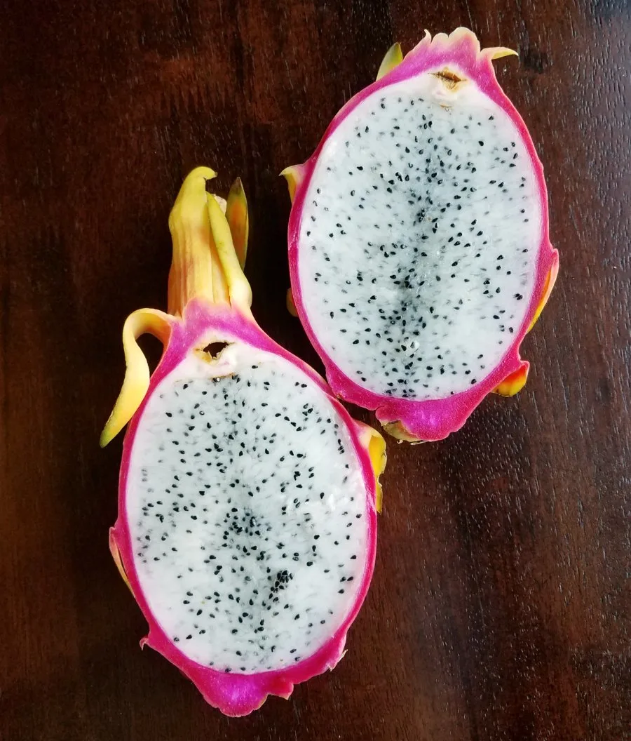 inside of dragon fruit with bright pink exterior, white flesh and black specks for seeds.