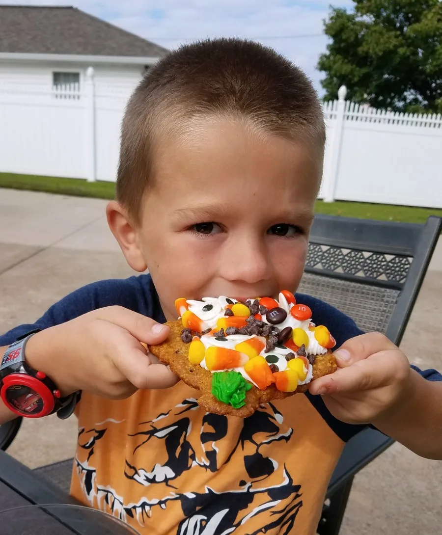 kid eating a cookie loaded with frosting and candy.