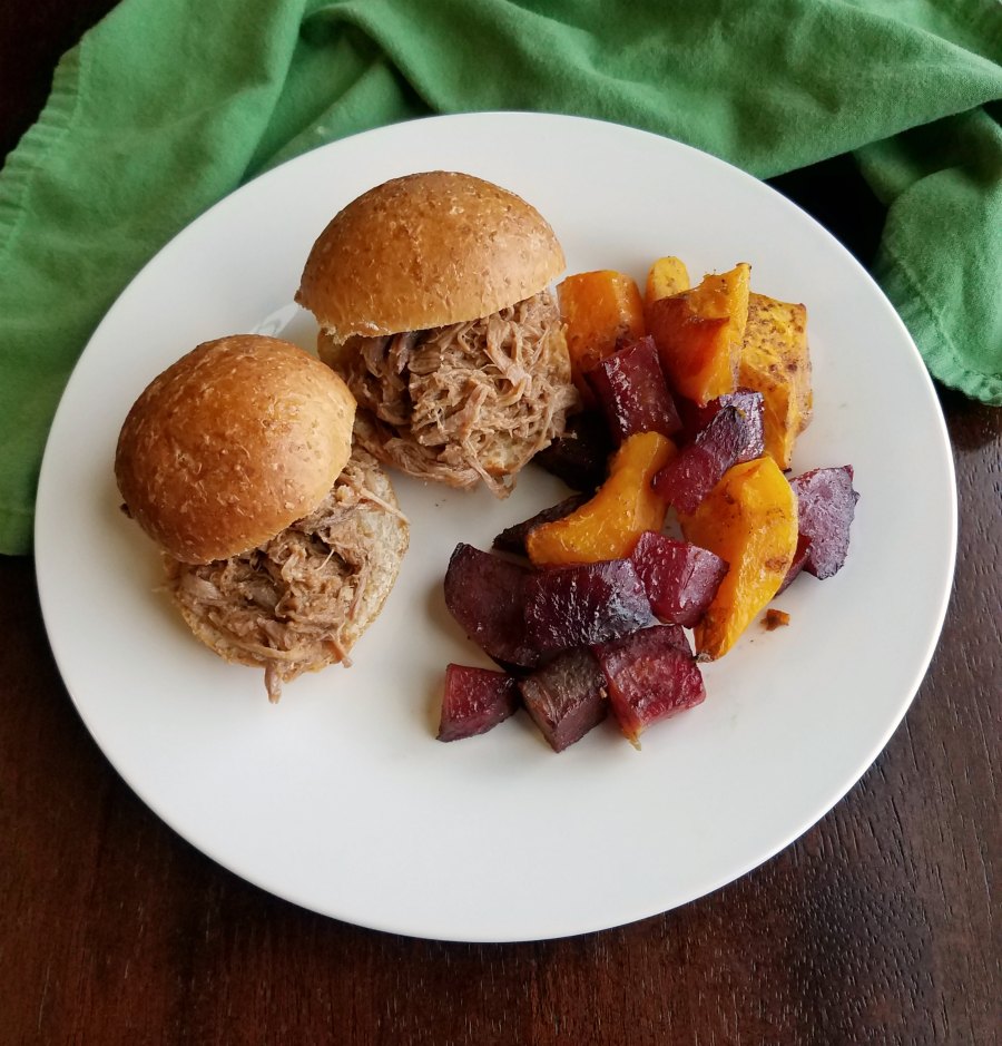 dinner plate with pulled pork sandwiches and roasted beats and squash.