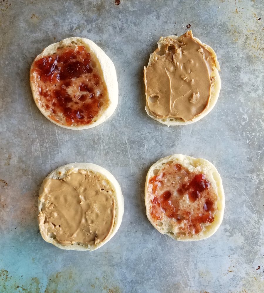 english muffin halves spread with peanut butter or jelly.