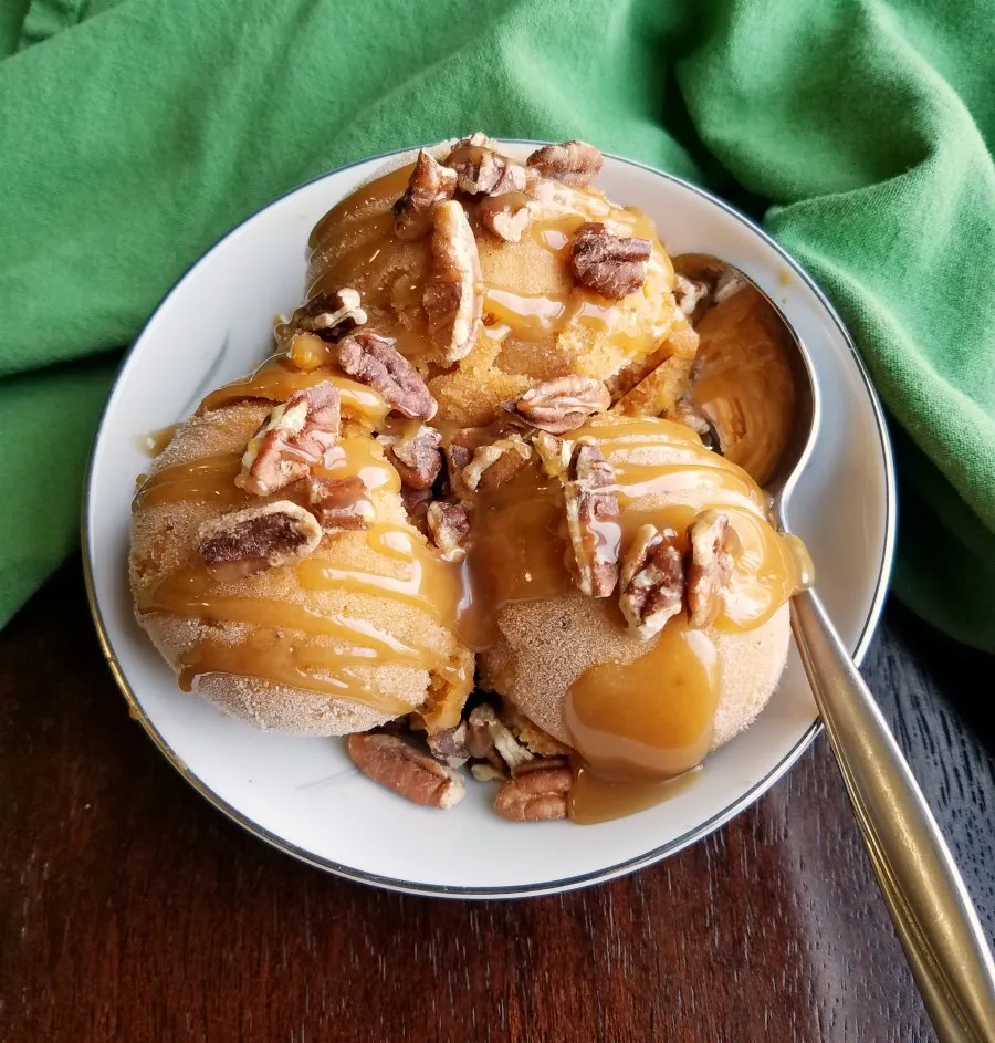 Bowl of pumpkin nice cream drizzled with caramel and topped with toasted pecans. 