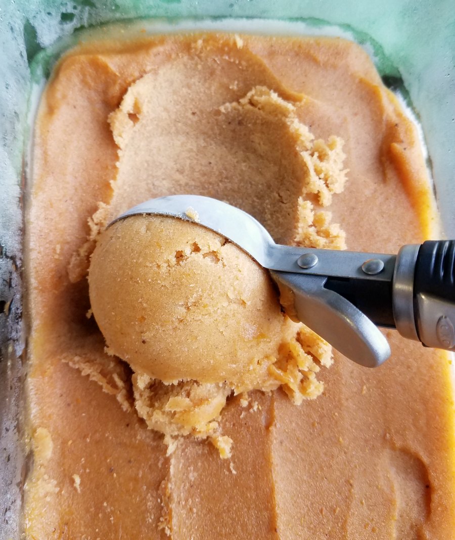 scooping out a ball of pumpkin ice cream with scoop.