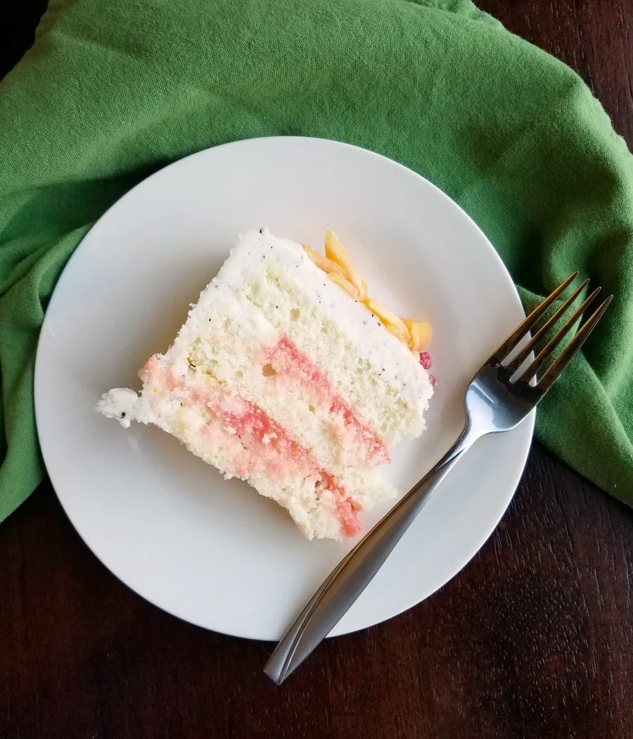 slice of white cake with pink blood orange curd filling between layers.