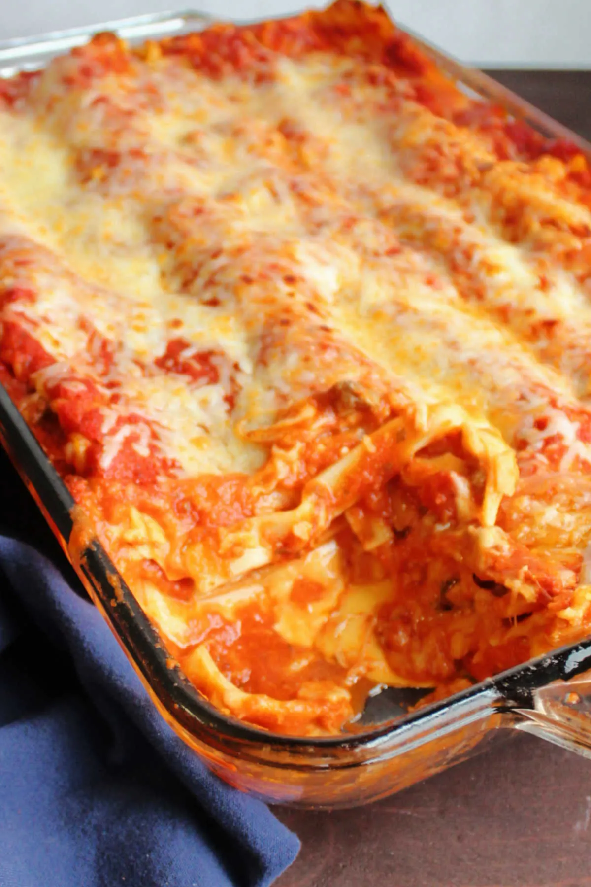 Pan of lasagna with layers of cheese, pasta and sauce with piece missing showing gooey velveeta in the middle.