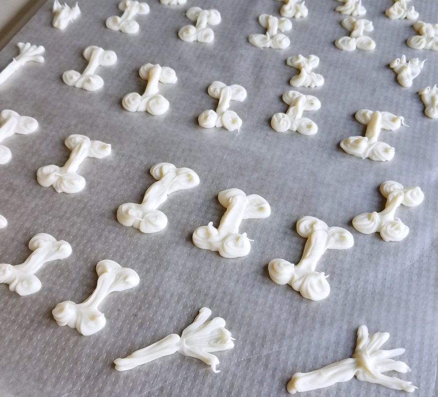 white chocolate bones and hands piped on wax paper.