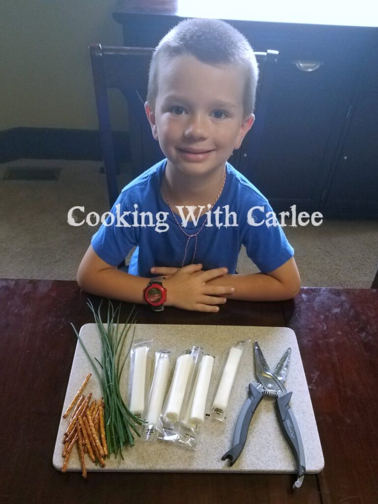 kid with cutting board of ingredients to make broomsticks.