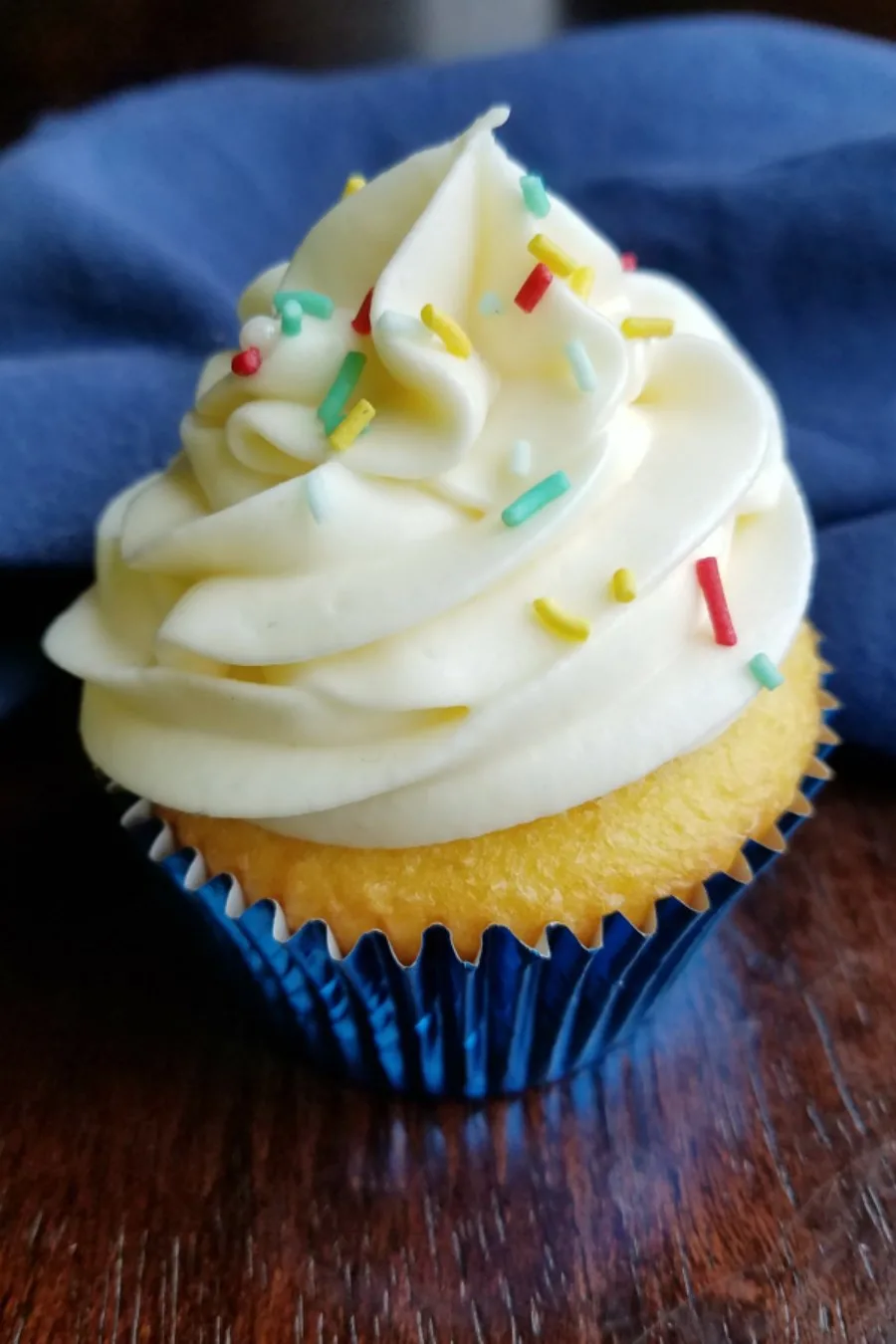 Cupcake topped with tall swirl of lemonade Russian buttercream and colorful sprinkles.