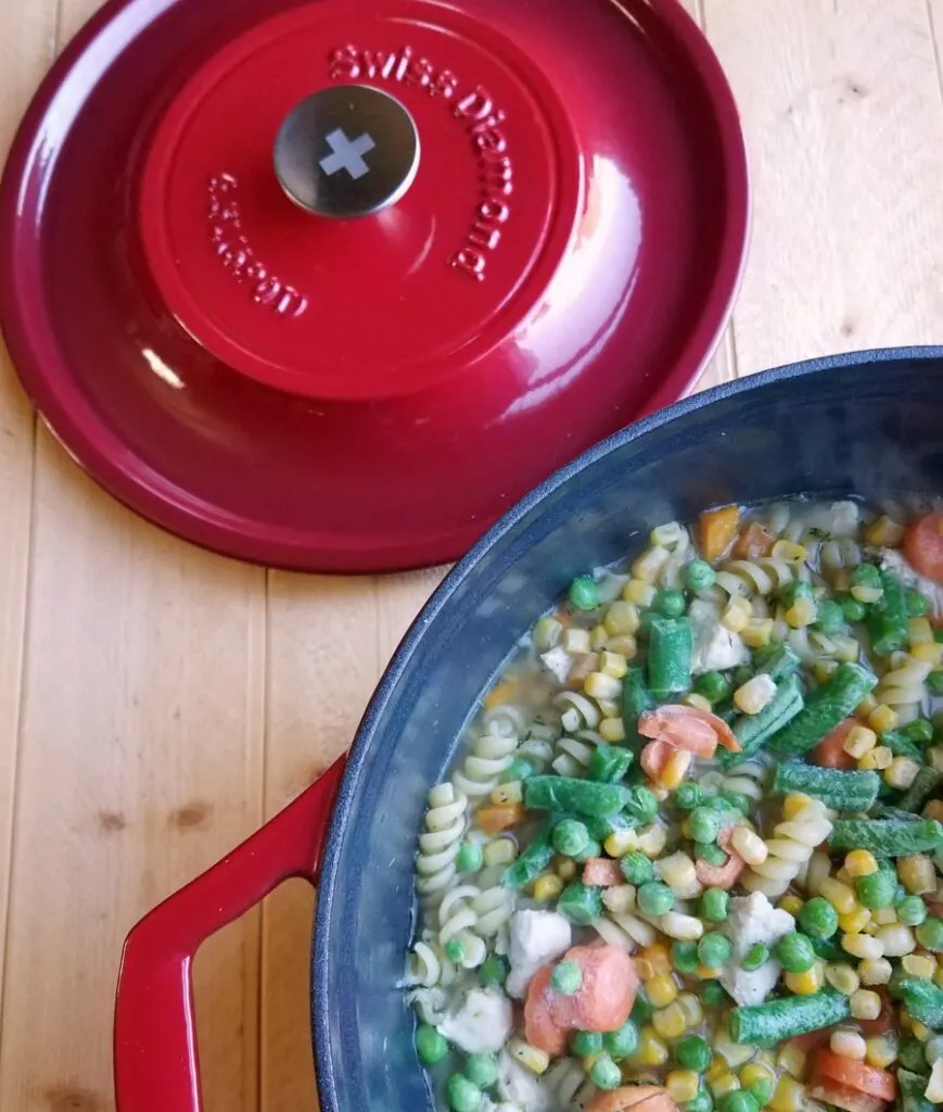 enameled dutch oven with pasta and veggies in it