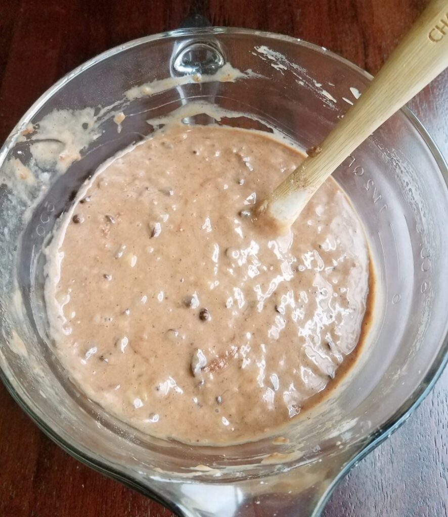 Glass mixing bowl filled with chocolate banana sourdough quick bread batter ready to go in pan.