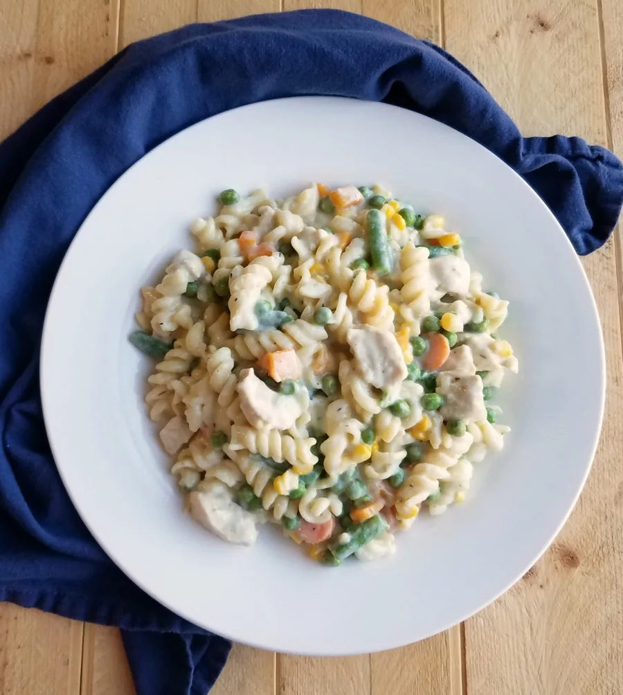 plate loaded with creamy pasta, chicken and veggies, read to eat.