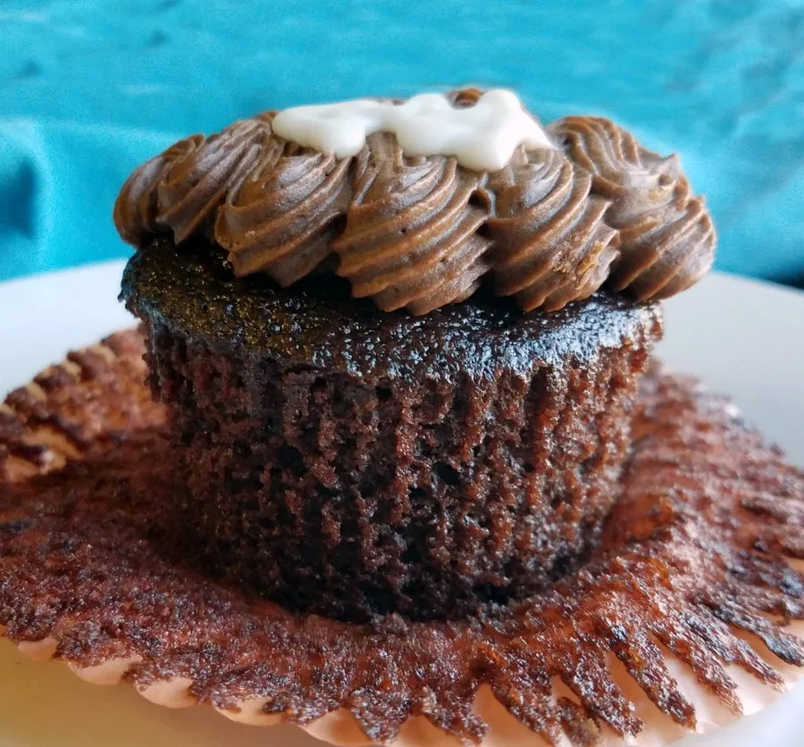 unwrapped devilishly good chocolate cupcake with chocolate frosting piped on top.