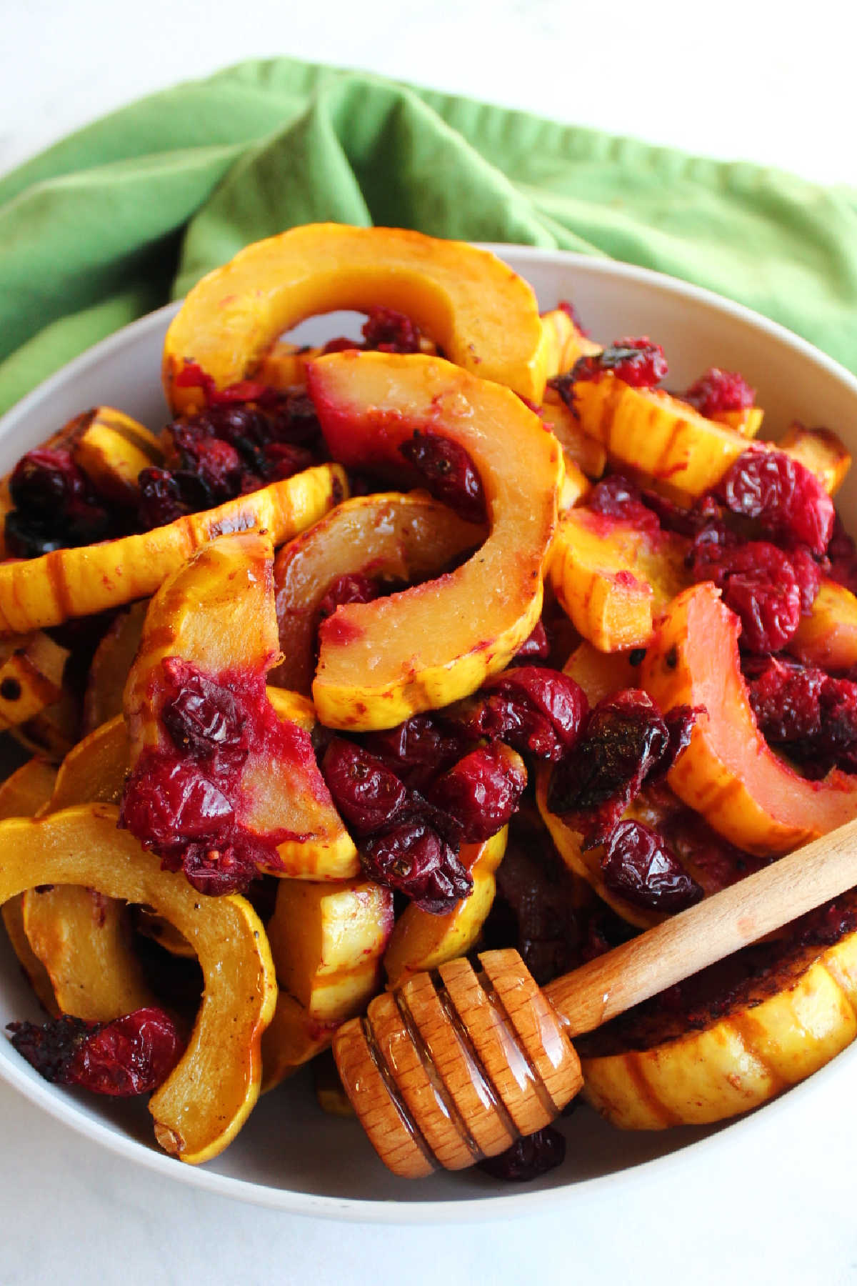 Serving bowl filled with roasted delicata squash and cranberries with honey and cinnamon.