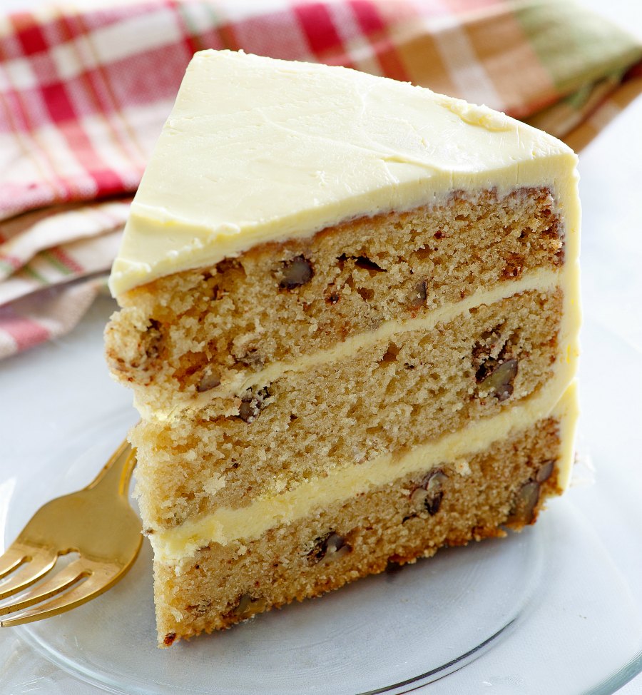 slice of triple layer cake studded with nuts and smooth frosting
