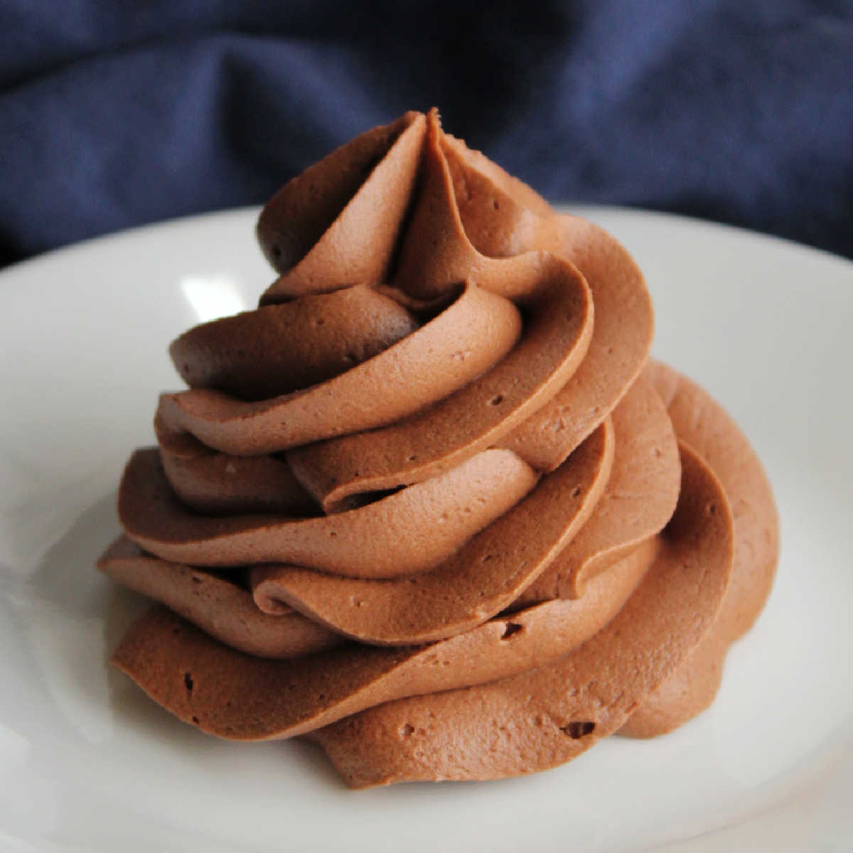 Swirl of piped chocolate fudge frosting with ruffled edges showing texture of icing.